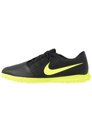 Black and neon yellow Nike soccer shoe with textured toe, low profile sole, and laces, shown in side view against white background.