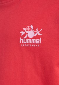 Rød bomulds t-shirt med et hvidt "hummel SPORTSWEAR" logo og et grafisk motiv af en blomst og en bold over teksten.