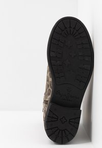 Botín de ante con estampado de leopardo y suela de goma negra que presenta un patrón de banda de rodadura resistente, cierre de cremallera y marca en la suela.