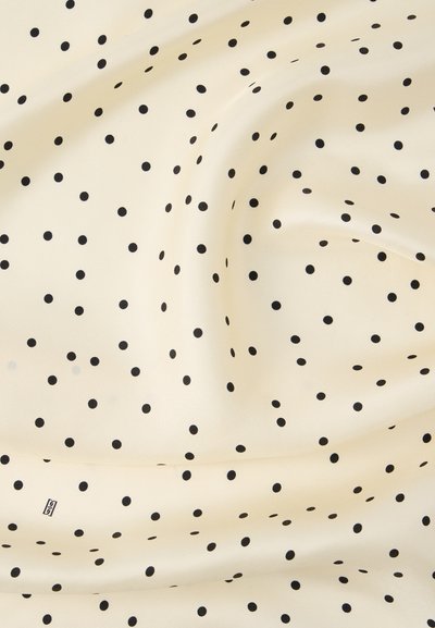Υφασμα κρεμ χρώματος με απαλό υφή και διάσπαρτες μικρές μαύρες πουά, ελαφρώς ζαρωμένο στο κέντρο.