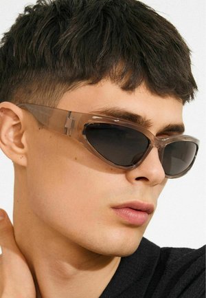 Cat-eye sunglasses with transparent brown frames and dark lenses. Notable angular design with visible hardware accents on the temples.