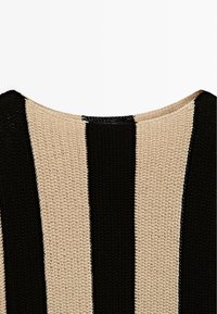Haut en tricot avec de larges rayures verticales noires et beige et un col rond.