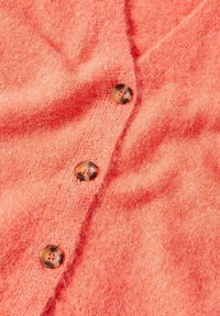 Cardigan tricoté rose corail doux avec trois boutons marron marbrés fermés sur le devant.