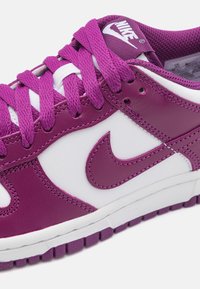 Baskets Nike violettes et blanches avec une tige en cuir lisse, une languette en mesh texturé et des lacets violets assortis. Semelle intermédiaire blanche et semelle extérieure en caoutchouc.