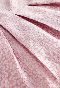 Roosa tekstuuriga kangas, millel on peen loomamuster ja voldid, mis loovad sügavust ja liikumist. Pehme, kerge materjal.
