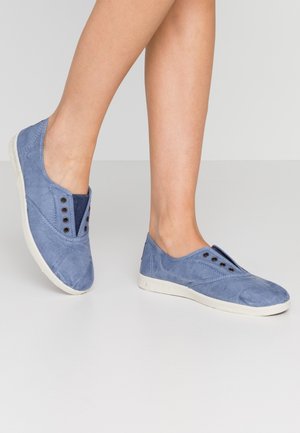 Light blue canvas slip-on shoes with textured surface, elastic side panels, decorative silver eyelets, and white rubber soles.