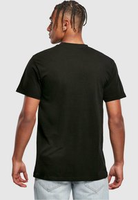 Sort bomulds t-shirt, korte ærmer, rund halsudskæring, flad kant. Bagsiden viser en glat tekstur uden grafik eller mønstre.