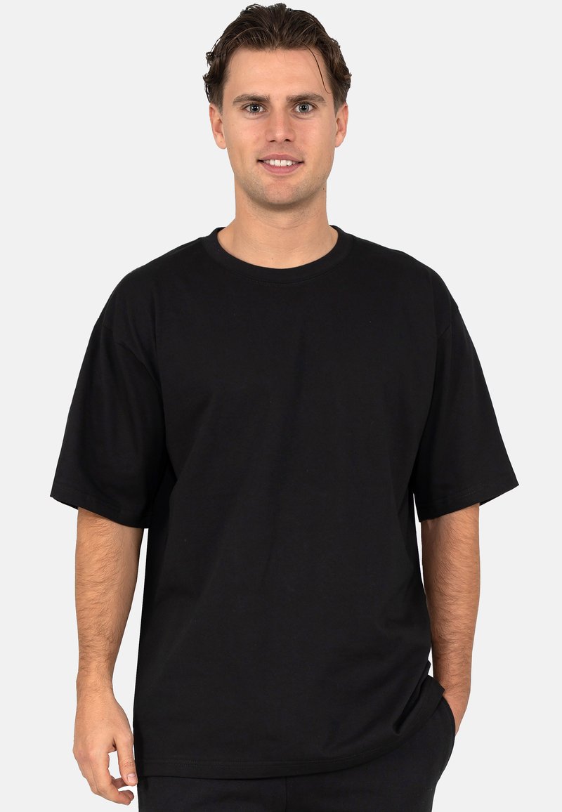 T-shirt en coton noir avec un col rond classique, des manches courtes et une coupe décontractée. Le tissu semble lisse avec des coutures minimales.