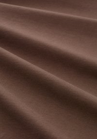 Bruine stof met een gladde textuur en een lichte glans, voorzien van zachte, subtiele kreukjes en een consistente rekbaarheid over het oppervlak.