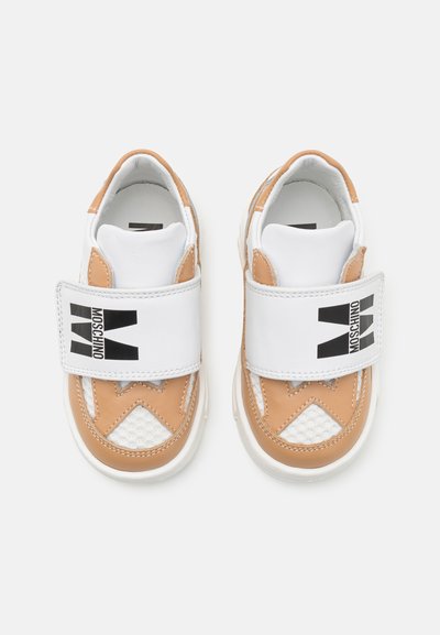 Ādas bērnu sporta apavi ar baltām un brūnām daļām, ar sieta paneļiem, Velcro jostu un Moschino logo uz jostas.