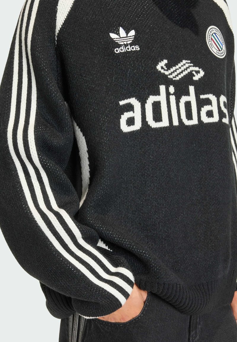 Black knitted Adidas sweater featuring a white logo and three white stripes on each sleeve. Ribbed cuffs and hem, showing distinct texture.