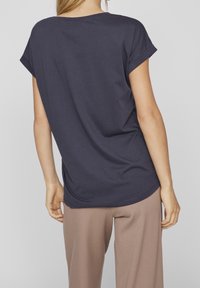 Námořnická modrá tričko s krátkými ohrnutými rukávy, kulatým výstřihem a volným střihem, vyrobené z měkké, texturované tkaniny.