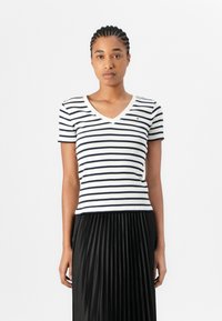 Stripet kortermet topp i hvit og marineblå, med V-hals. Materialet er mykt med en slim fit. Lite logoakcent på brystet.