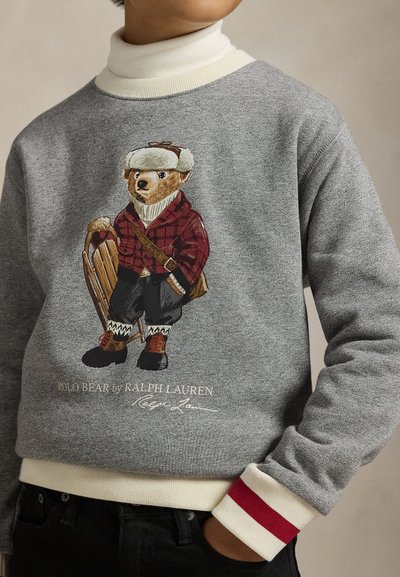 Γκρι φούτερ με αρκουδάκι ντυμένο για τον χειμώνα. Ριμπ μανσέτες με κόκκινο ένθετο, κεντημένο λογότυπο και λεπτομέρειες με έλκηθρο. Μαλακή υφή.