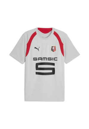 Maillot de sport blanc avec des accents rouges aux épaules, logo Puma noir, écusson du Stade Rennais FC, et texte noir "SAMSIC" ainsi qu'un grand "S" stylisé sur le devant.