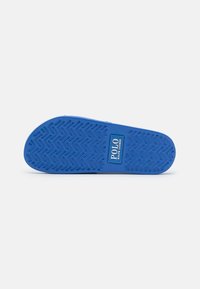 Blå gummisula av en slide sandal med zigzag-mönstrat grepp och "Polo Ralph Lauren" logotyp i mitten.
