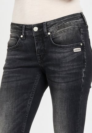 Black denim jeans featuring a slim fit, faded texture, five-pocket design, metallic hardware, and a branded tag on the front pocket.