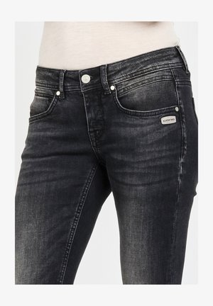 Black denim jeans featuring a slim fit, faded texture, five-pocket design, metallic hardware, and a branded tag on the front pocket.