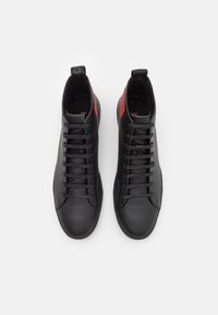 Svarta höga sneakers i texturerad läder, med en elegant design, platta snören och röda detaljer på hälfliken.