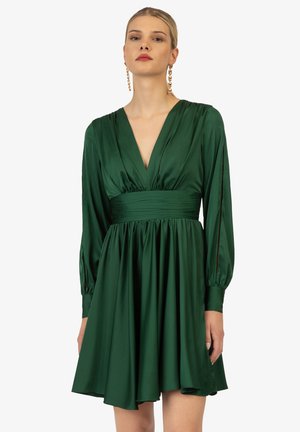 Green satin dress with a deep V-neck, long sleeves, and a fitted waist. Flowy skirt with a slight sheen, showcasing elegant drape and movement.