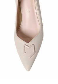 Zapato de tacón alto de cuero beige con punta afilada, que presenta un logotipo recortado y un acabado interior suave y texturizado.