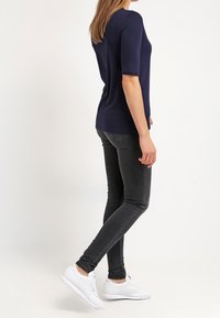 Marinblus med kort ärm och en kroppsnära silhuett, förd med svarta skinny jeans och vita sneakers. Slät tygkvalitet och klassisk design.