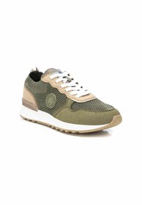 Zapatilla ligera en verde oliva y beige, con parte superior de malla, cordones blancos y acentos texturizados. Suela de goma acolchada con detalle del logo.