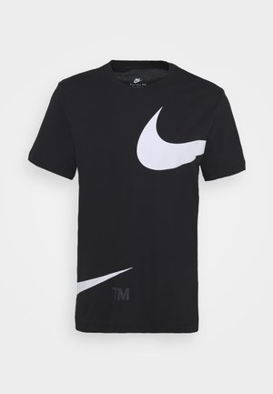 Sort T-shirt lavet af bomuld med store hvide Nike swoosh-logoer og "TM"-tryk i det nederste hjørne. Korte ærmer, rund hals.