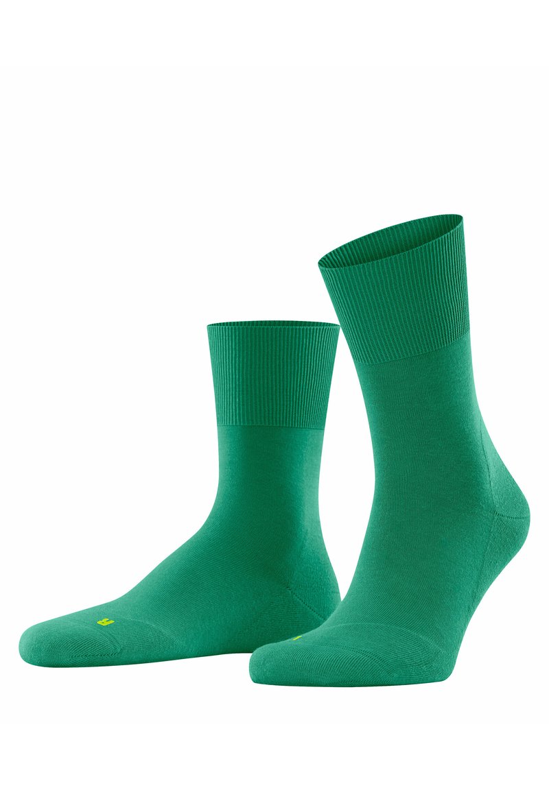 Ein Paar grüne Socken bis zur Mitte der Wade mit geripptem Bund, geformt für den rechten und linken Fuß, vor einem weißen Hintergrund präsentiert.