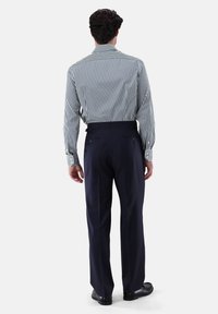 Gestreifte Langarmbluse in Schwarz und Weiß, kombiniert mit marineblauen hoch taillierten Hosen. Die Hosen haben zwei Gesäßtaschen und eine glatte Textur.