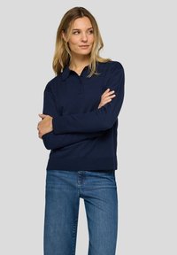 Dunkelblaues Pullover-Sweatshirt mit kragenförmigem Ausschnitt, drei-Knopf-Leiste, gerippten Bündchen und Saum, kombiniert mit blauen Jeans.