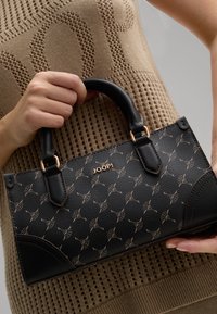 Black textured handbag with a geometric pattern, featuring gold hardware accents and a structured design. The handle is sleek and rounded.