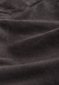 Bavlnená tkanina tmavosivej farby s diagonálnou rebrovanou textúrou, mäkké záhyby a jemný lesk na povrchu.