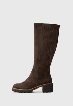 Brown suede knee-high boot featuring vertical panel detailing, rounded toe, and a chunky black heel with a textured sole.