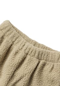 Fleece-Bekleidung in Hellbeige mit strukturierter Oberfläche. Mit elastischem Bund und gerafften Falten, die die Weichheit und den Komfort erhöhen.