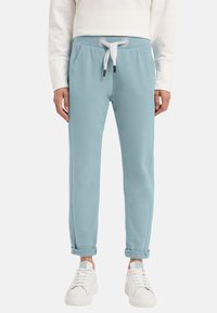 Helles blau Jogginghosen aus weicher Baumwolle. Mit umgeschlagenen Säumen, seitlichen Taschen und einem verstellbaren Bund mit kontrastierenden weißen Schnürsenkeln.