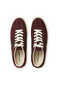 Burgundski nubuk tenisice s kremastim vezicama, crnim bočnim prugama i bež gumiranim potplatima. Imaju podstavljeni jezik i uložak za udobnost.