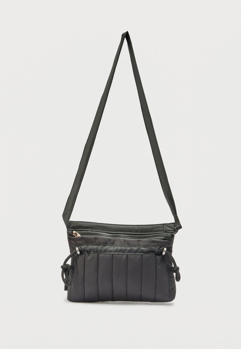 Μαύρη κοντή τσάντα ώμου με σχέδιο καπιτονέ, μακρύ ρυθμιζόμενο λουράκι, μπροστινή τσέπη με φερμουάρ και πλαϊνές λεπτομέρειες με κορδόνι.