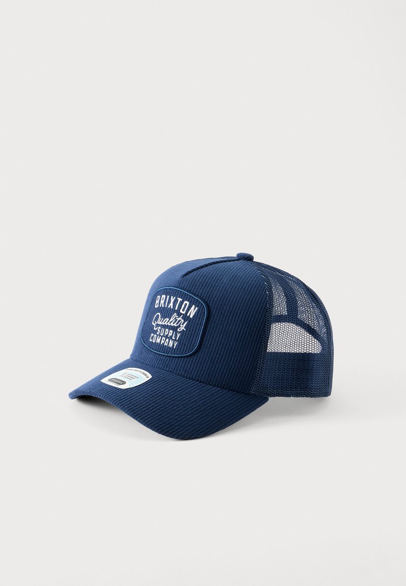 Σκούφος Brixton τύπου trucker σε ναυτικό μπλε με πλέγμα στο πίσω μέρος και καμπυλωτό γείσο, με ταμπέλα που φέρει λευκό κείμενο "Brixton Quality Supply Company."