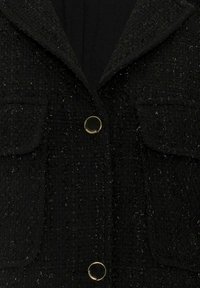 Schwarze, strukturierte Jacke mit gewebtem Finish, ausgestattet mit goldfarbenen Knöpfen und zwei Vordertaschen mit Klappen. Design mit Reverskragen.