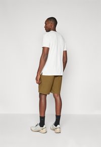 Hvit t-skjorte med korte ermer kombinert med khaki shorts, svarte sokker og grå joggesko med lyse detaljer. Enkel og funksjonell design.