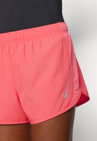 Roze atletske kratke hlače od lagane tkanine s elastičnom strukom i mrežnim bočnim panelima, s malim sivim Nike logotipom.