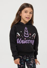 Czarna bluza z kapturem z purpurowym brokatowym nadrukiem "Jednorożec", z rogiem jednorożca i gwiazdkami. Ribbat hem i mankiety. Połączona z wzorzystymi legginsami.