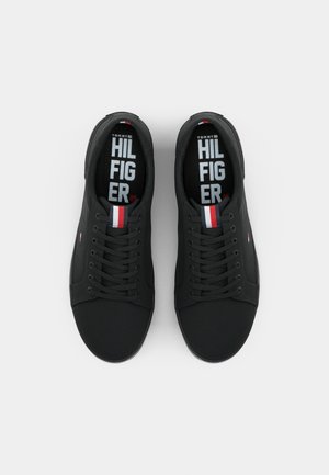 Par sorte lavtop sneakers med sorte snørebånd, rød, hvid og blå stribet tungeetiket og hvid tekst på sorte indlægssåler.