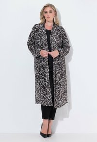 Läcker leopardmönstrad, lätt lång kimono-jacka med öppen front, flödande ärmar och textilmaterial, tillsammans med svart topp och utsmyckade byxor.