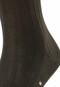 Calcetines de color verde oscuro con superficie texturizada y costuras claras en contraste, que cuentan con un talón y una punta reforzados para mayor durabilidad.