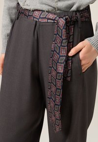 Pantaloni grigi con cintura blu scuro decorata a motivi geometrici in rosso, verde e crema. Vestibilità slim con una texture liscia.