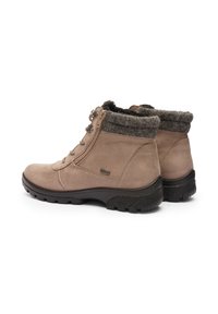 Een paar beige suède enkellaarzen met zwarte rubberen zolen, een zijrits, vetersluiting aan de voorkant en een grijze wollen voering aan de bovenrand.