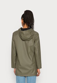 Imperméable à capuche vert olive, fabriqué en matériau lisse et imperméable. Présente des manches longues et une coupe décontractée, avec un design simple.