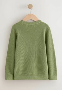 Grönstickad tröja hängande på en trägalge. Har en ribbad textur och en rundad halsringning, med långa ärmar och en rak fåll.